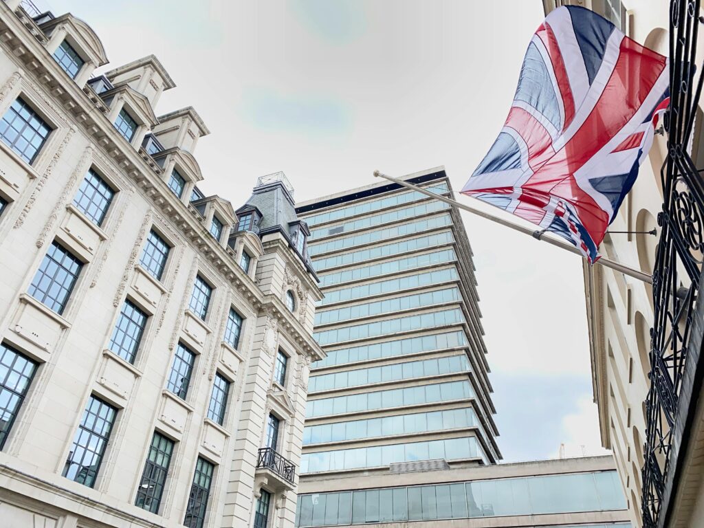 A striking view of London buildings adorned with a Union Jack flag fluttering in the wind.
