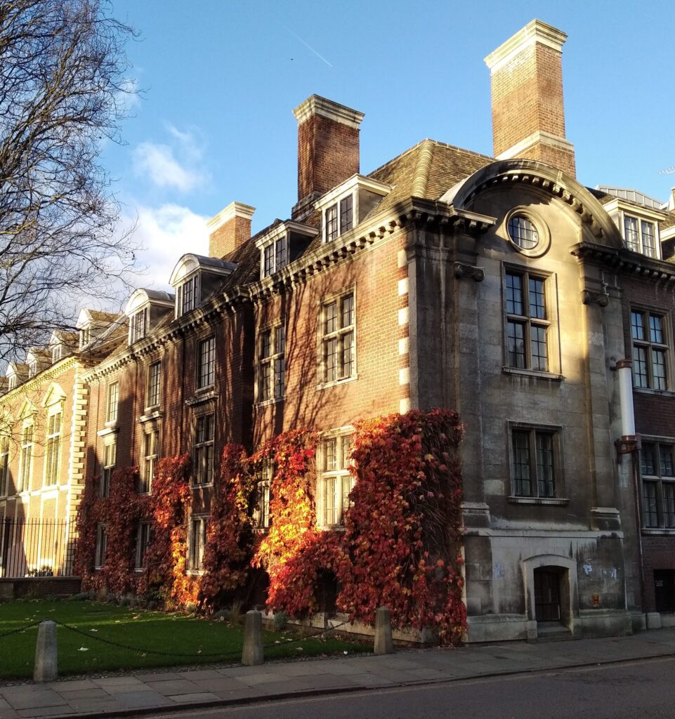 Beautiful ivy-covered building in Cambridge, UK, during fall with vibrant autumn foliage.